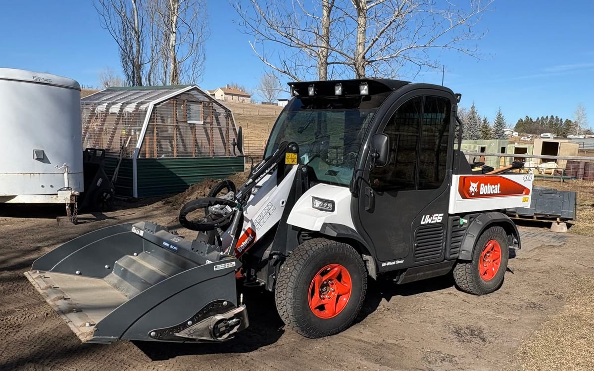 Bobcat Toolcat utility vehicle with a rake attachment parked in a yard