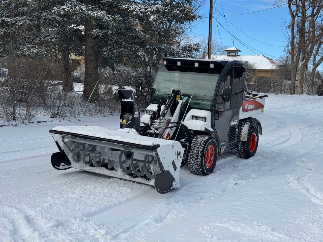 Bobcat Toolcat with a front snowblower attachment on a snowy street