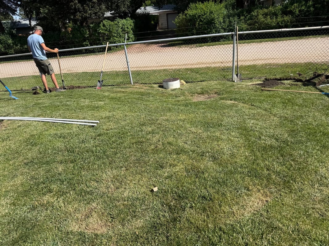 Crew member laying out a sprinkler system in a fenced back yard