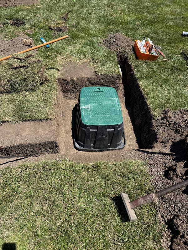 Green-lid valve box set in a trench in a lawn