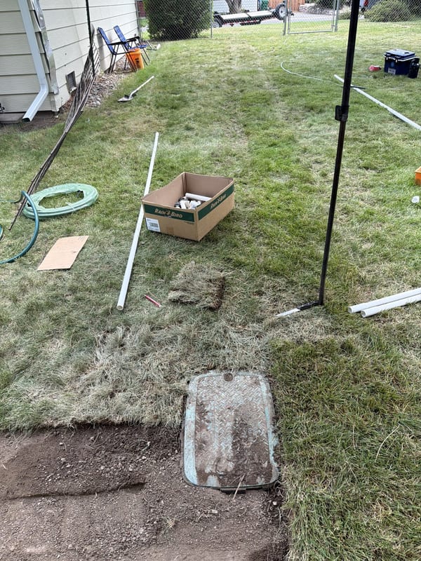 Old valve box lid in a lawn with pipe and supplies ready