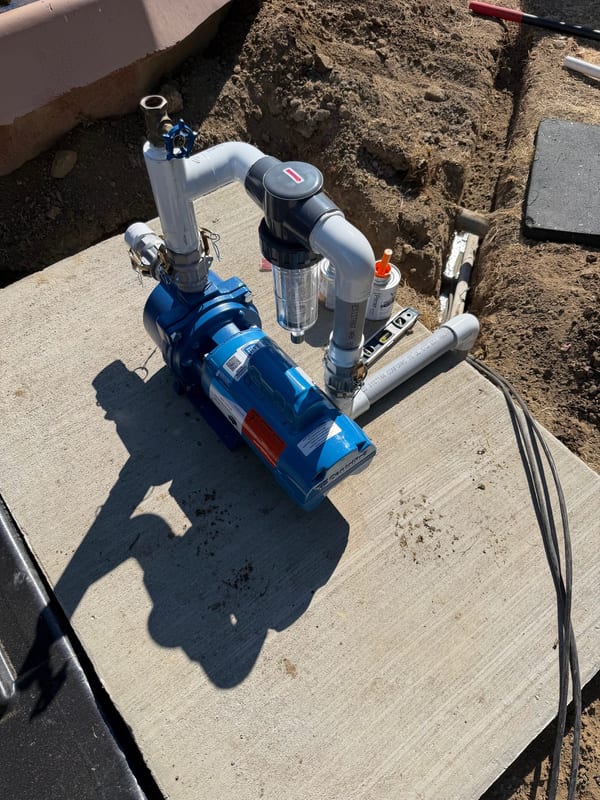 Irrigation pump with a filter and PVC plumbing on a concrete pad